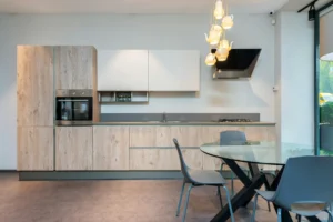 Tanie krzesła do kuchni – szare plastikowe krzesła przy okrągłym szklanym stole w nowoczesnej, jasnej kuchni